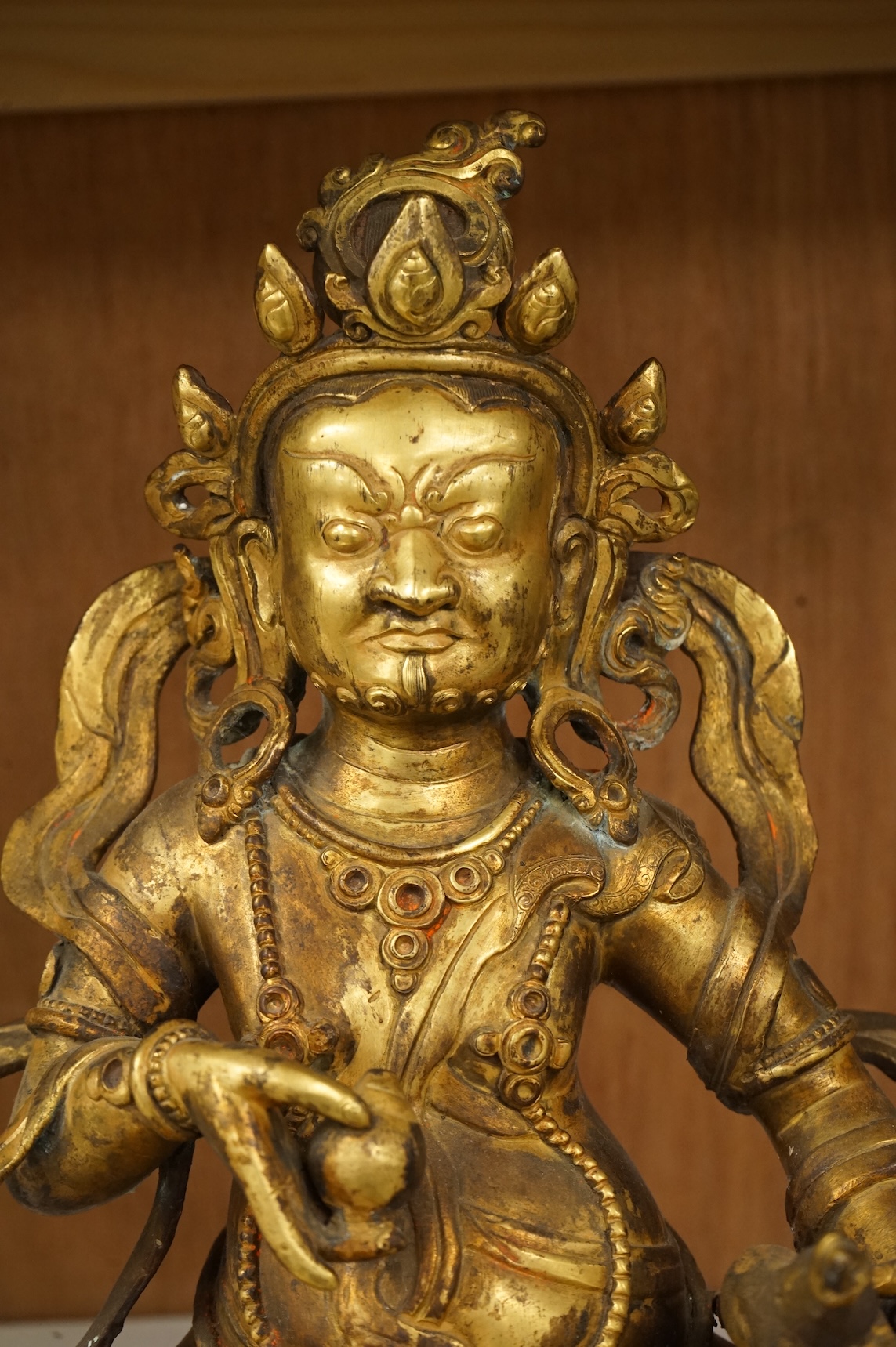 A large Sino-Tibetan gilt-bronze seated figure of Jambhala, 28cm high